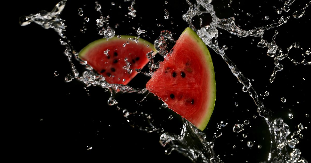Soczyste kawałki arbuza rozpryskujące się w wodzie na czarnym tle