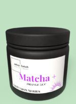 Słoik z ciemnego szkła z etykietą Johny Catch Matcha + Orange Zen z serii Liofusion, zawierający matchę ceremonialną z liofilizowaną pomarańczą i imbirem.