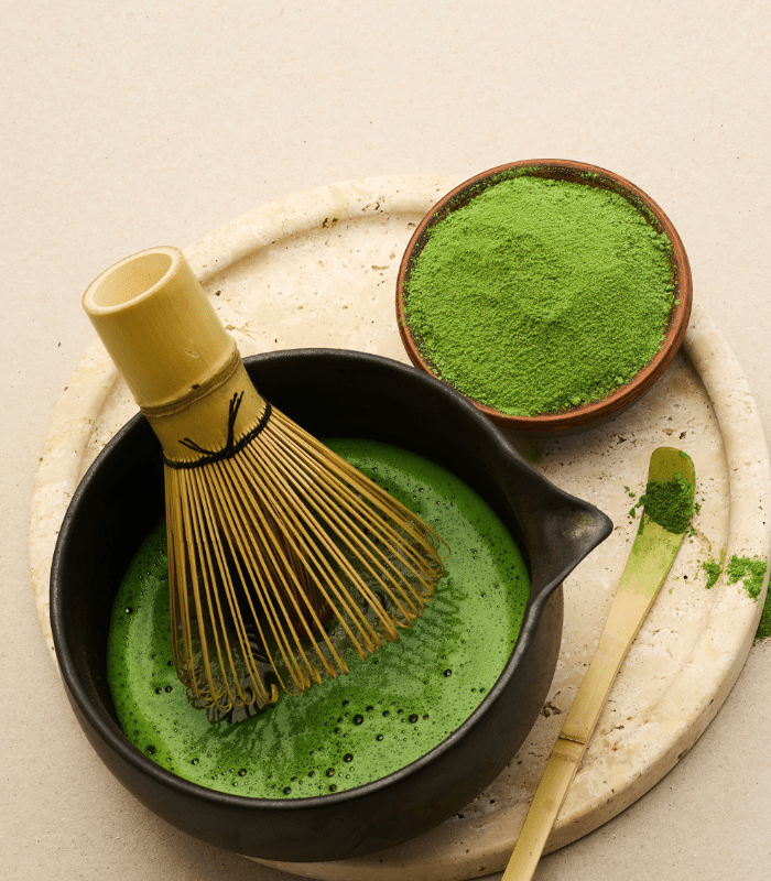 Przygotowanie matchy ceremonialnej w miseczce z bambusową trzepaczką chasen, proszek matchy obok